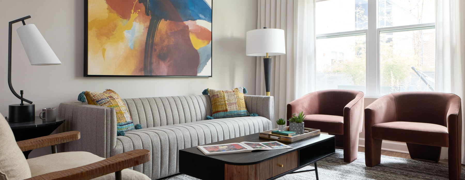 Bright, modern living room at Sloan Clarendon apartments in Arlington, VA, with a striped sofa, abstract artwork and large windows