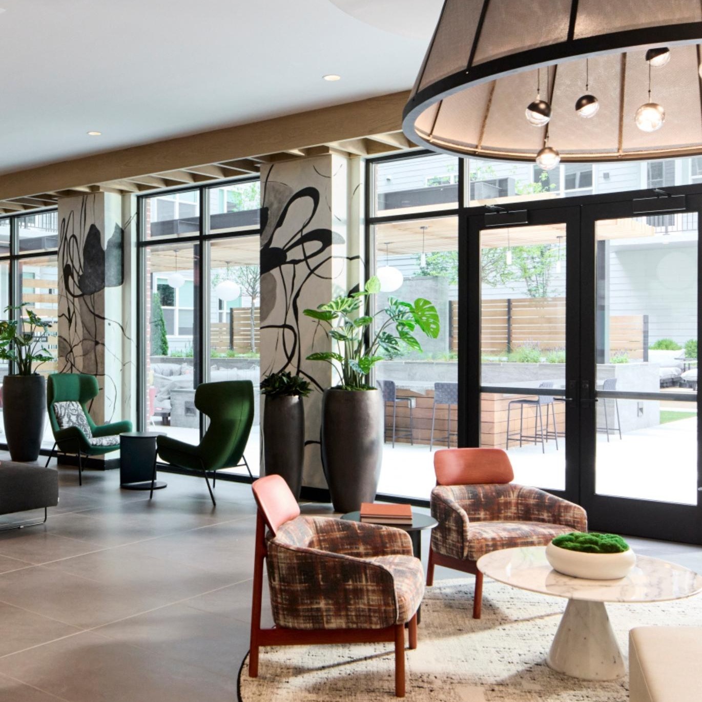 a room with a large glass door and a table with chairs and a plant in it