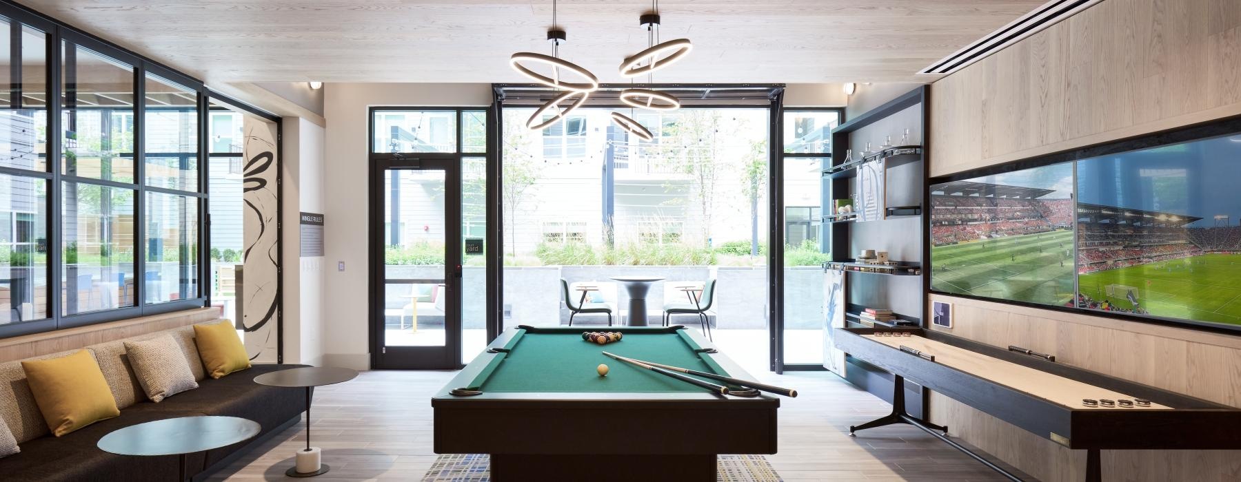 a room with a pool table and a large window with a large screen